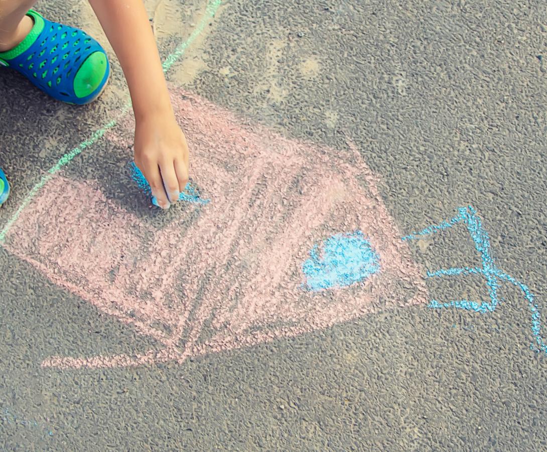 kid drawing on the sidewalk with chalk