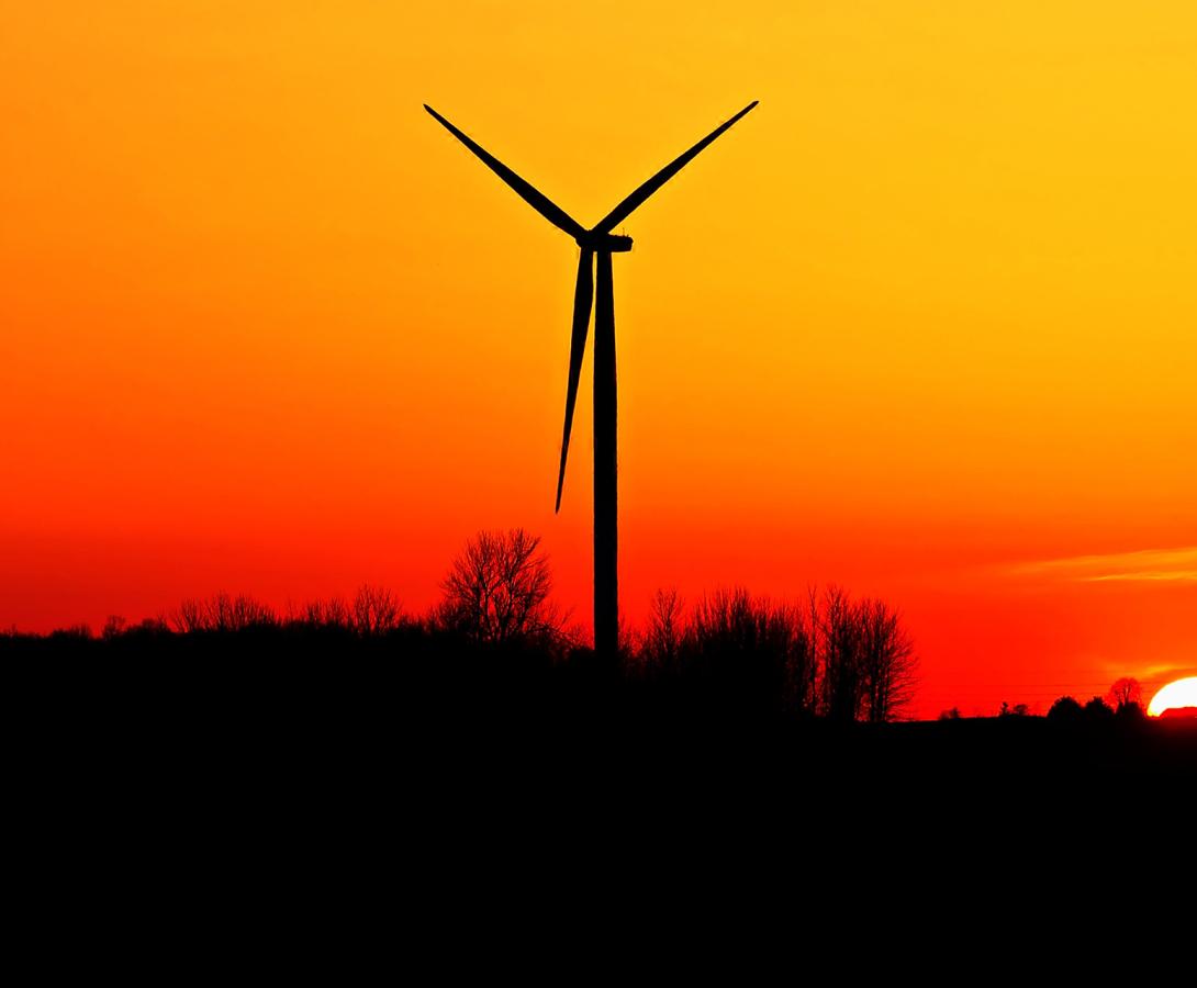 Wind Turbine with sunset behind on farmland