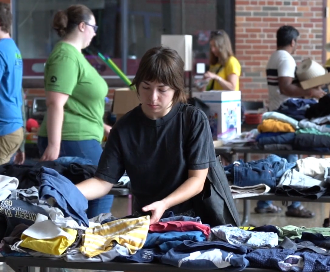 A woman sorting through piles of clothes