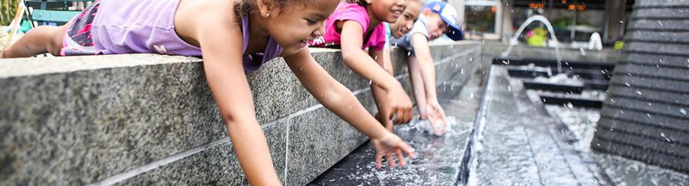 Kids playing in a water fountain 