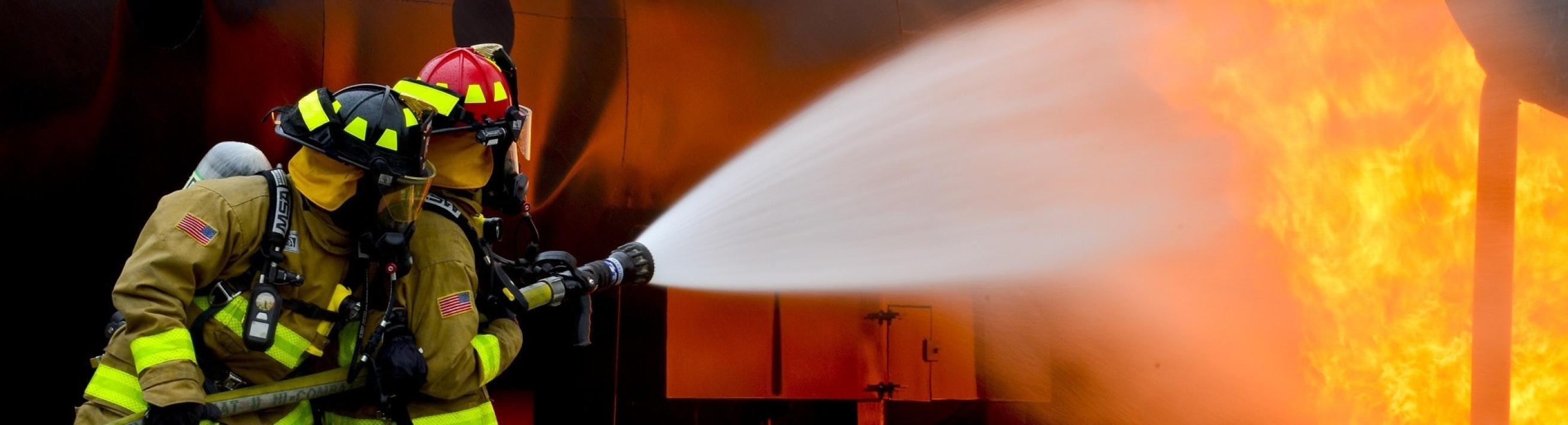 Two firefighters spraying a fire with a hose