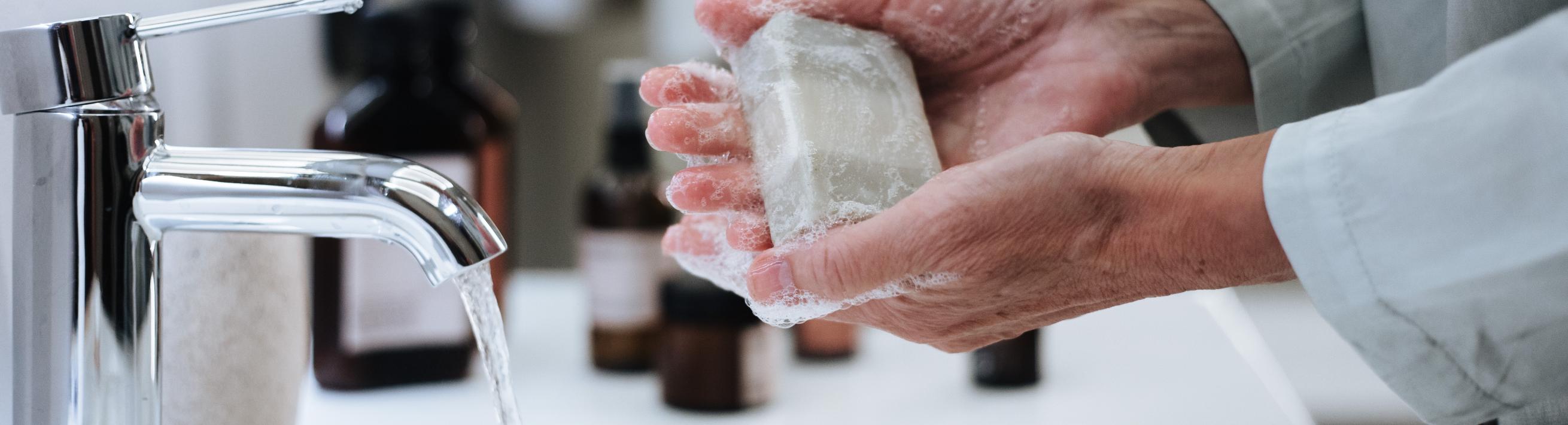 A person washing their hands with a bar of soap.