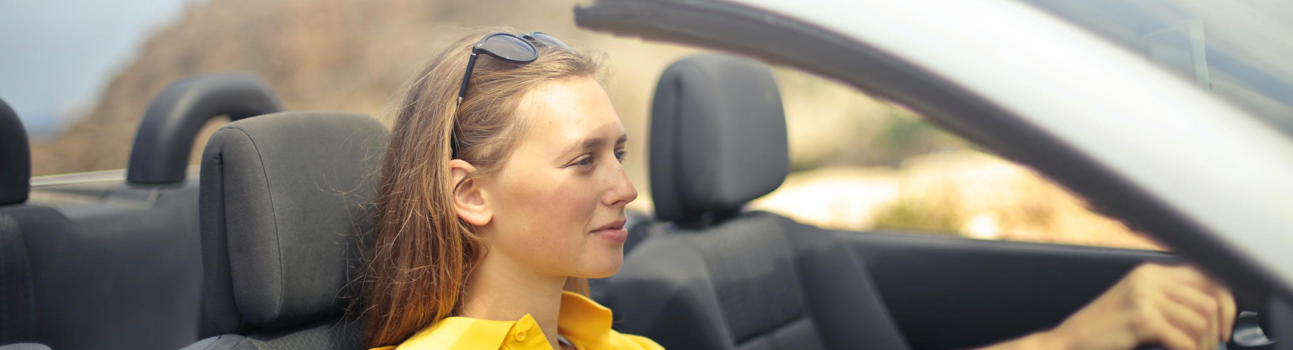 A woman driving in a car with a convertible top