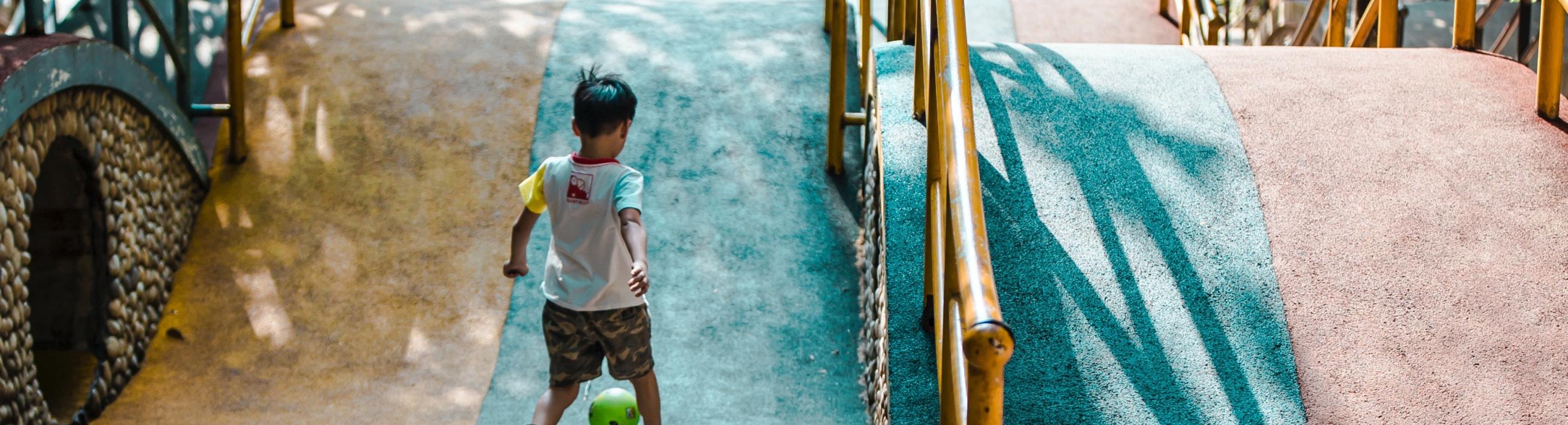 A kid playing with a ball at a playground