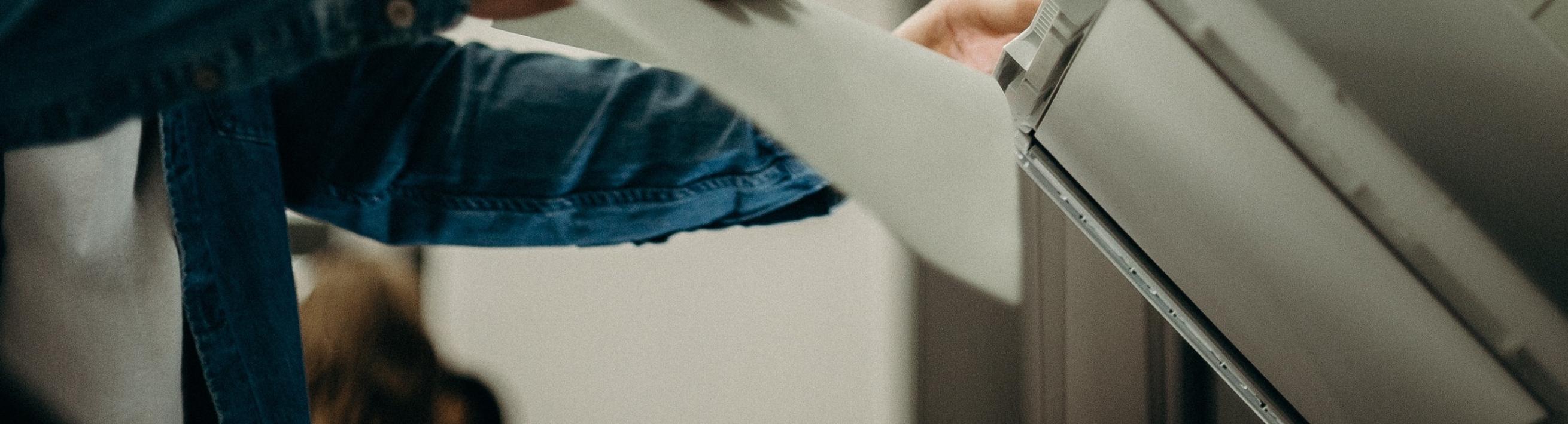 A person putting a piece of paper into a copier