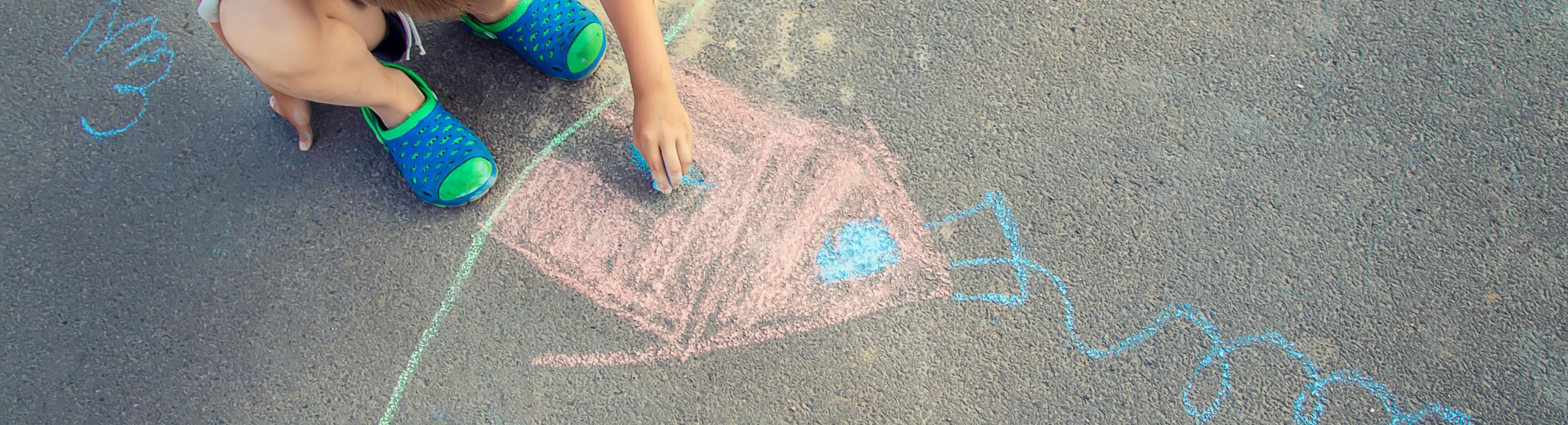 kid drawing on the sidewalk with chalk