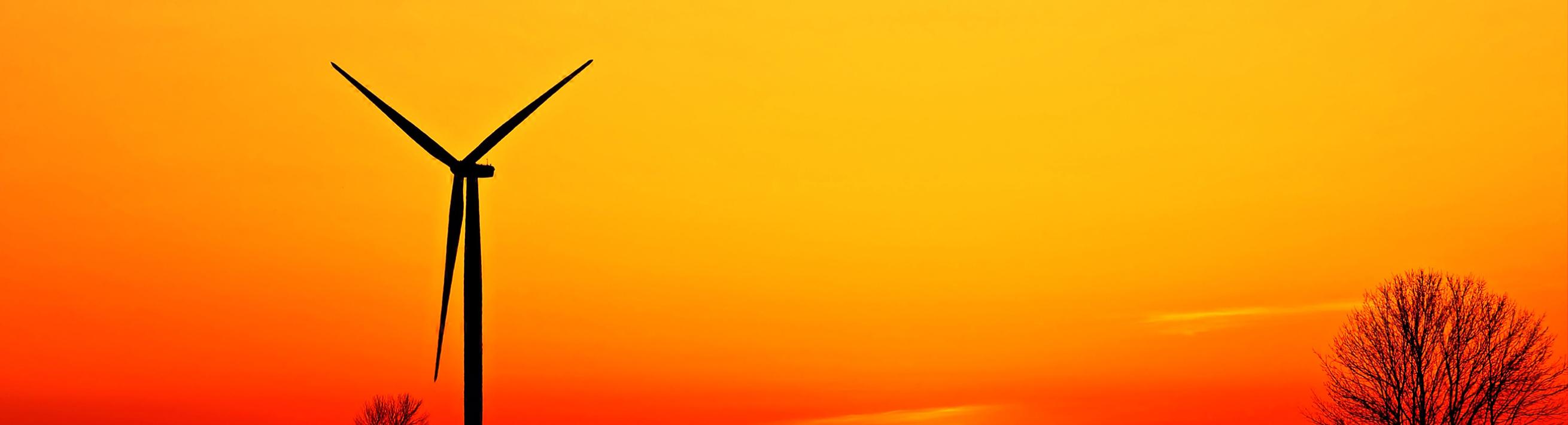 Wind Turbine with sunset behind on farmland