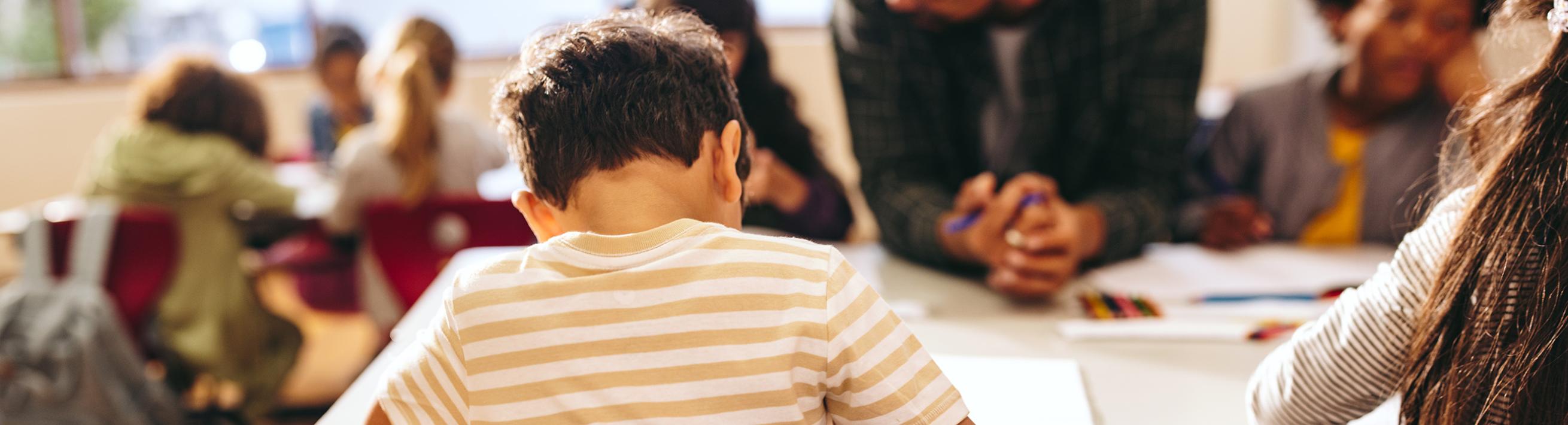 Child learning in classroom, adults helping.