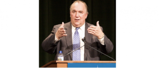 John Engler standing at a podium, talking with his hands